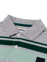 Remera polo gris melange de manga corta Caterpillar, con franjas horizontales en tonos verde oscuro y menta en el pecho, cuello camisero con botones y parche de silicona con logo.