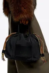 Bolso bandolera pequeño de nylon negro con estructura blanda, doble asa de mano y correa regulable. Cuenta con cierre de cordón ajustable y etiqueta con logo grabado en el frente.