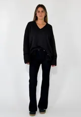 Sweater de punto azul marino con cuello en V, mangas largas con puños acanalados y detalle de línea en color marrón en el cuello y puños. Presenta un pequeño aplique decorativo en la parte inferior.