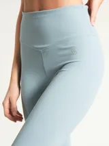 Calza deportiva de tiro alto con largo hasta el tobillo, confeccionada en tejido técnico elástico de color celeste. Presenta un diseño minimalista sin bolsillos y un pequeño logo bordado en la cadera.