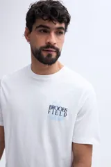 Remera blanca Brooksfield de manga corta y fit regular, con estampa en la espalda en tonos celestes y oscuros.