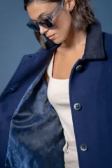 Tapado de corte recto con estampado de pata de gallo en tonos azul y gris. Presenta cuello camisero y detalles en los puños en color negro, cierre frontal con botones y bolsillos laterales.