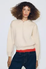 Jersey de punto con cuello tipo polo, manga larga con puños y cierre frontal con botones. Presenta un bolsillo de plastrón en el pecho y diseño de corte holgado.