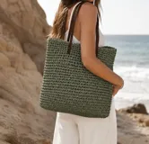 Bolso de playa verde de tejido tipo crochet, con asas de hombro en color marrón oscuro.
