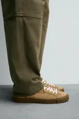 Zapatilla de cordones confeccionada en piel con acabado de serraje. Presenta un diseño liso con detalle en color a contraste en la pieza del talón y suela plana de goma a contraste.