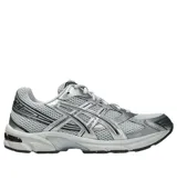 Championes Asics Gel-1130 de color gris y plateado, con detalles en negro, confeccionados en malla transpirable y refuerzos sintéticos. Incorporan tecnología de amortiguación en la suela y el característico diseño lateral de la marca.