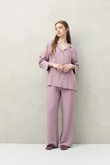 Camisa de pijama color blanco tiza con rayas verticales en relieve, de silueta clásica y caída fluida. Presenta cuello camisero, cierre frontal con botones y detalles de vivo rosado en cuello, puños y solapas.