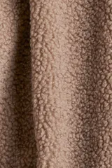 Campera oversized de sherpa con cuello elevado, cierre frontal y mangas largas amplias de hombros caídos.