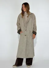 Tapado largo de paño de lana color beige con diseño de espiga, cuello con solapas, cierre con dos botones y bolsillos laterales.