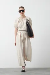 Falda larga plisada color marrón, de silueta amplia y caída fluida.