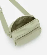 Bolso bandolera de estilo deportivo en color verde claro, confeccionado en poliéster. Cuenta con cierre principal de cremallera, bolsillo frontal con cierre, bolsillo trasero con cierre a presión, asa larga desmontable y regulable, y logo de la marca en relieve en la parte frontal.