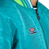 Campera reversible Umbro color turquesa con cuello, puños y dobladillo a rayas verdes, azules y blancas. Tiene cierre frontal y logo bordado en el pecho.