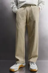Pantalón jogger de corte relajado confeccionado en tejido compacto de algodón. Presenta cintura elástica con cordón interior, bolsillos frontales en la cadera y un bolsillo trasero de plastrón.