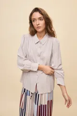 Camisa de manga larga color celeste, con cuello clásico y botonadura frontal. Presenta un calce relajado, con mangas amplias y puños anchos.