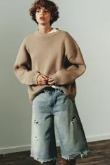 Jersey de punto liso con diseño oversize, cuello redondo y manga larga con puños acanalados.