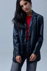 Blazer de eco cuero negro con cuello de solapa, cierre frontal con botones y bolsillos aplicados en la parte delantera. Cuenta con forro interno a tono.
