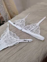 Conjunto de lencería compuesto por un bralette triangular de encaje con breteles regulables y una tanga colaless regulable con detalle de encaje.