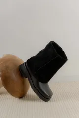 Bota de caña media combinada en cuero vacuno y gamuza, con diseño de solapa superior y punta cuadrada. Cuenta con suela de goma plana y tacón bajo.