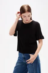 Remera negra de viscosa con textura acanalada, cuello redondo y mangas cortas terminadas en volados.