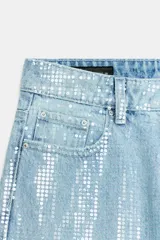 Pantalón jeans de tiro medio, pernera recta y diseño de cinco bolsillos, recubierto de lentejuelas brillantes en tono celeste. Cuenta con cierre frontal de cremallera y botón metálico.