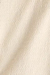 Vestido corto de tejido bouclé color beige, con escote redondo, espalda en V y mangas francesas. Cuenta con bolsillos decorativos con botones dorados en la cintura y falda con vuelo.