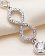 Pulsera de plata 925 con diseño de símbolos de infinito pavé de circonias y dije colgante circular con circón central.