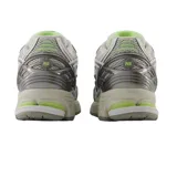 Championes New Balance modelo 1906R, de diseño técnico y deportivo en tonos gris, blanco y plateado, con detalles en verde lima. Presenta una estructura de malla transpirable con refuerzos sintéticos y entresuela amortiguada.