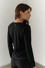 Remera blanca de manga larga con cuello redondo y costuras decorativas en contraste de color negro.