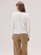 Remera de manga larga en color negro, con diseño de cuello redondo y terminaciones con vivos en contraste color beige. Presenta un corte recto y minimalista.