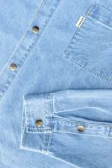 Camisa de jean celeste, de corte clásico, con cuello abotonado, manga larga y bolsillo en el pecho.