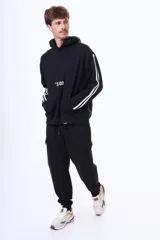 Buzo tipo canguro de felpa color negro, con capucha, bolsillo frontal tipo canguro, estampa frontal con texto y detalle de tres líneas blancas en las mangas.