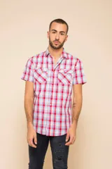 Camisa de manga corta con estampado de cuadros en tonos rojo, blanco y celeste. Presenta cuello clásico, cierre frontal con botones y dos bolsillos delanteros con solapa en el pecho.