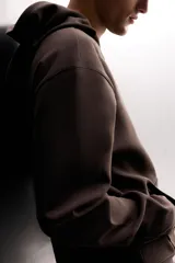Sudadera de hombre Zara Athleticz de ajuste relajado (relaxed fit), color marrón, confeccionada en tejido técnico compacto con mezcla de algodón y elasticidad. Cuenta con cuello con capucha ajustable con cordones negros, manga larga, bolsillo frontal tipo canguro con un pequeño bolsillo termofijado con cierre, y acabados con rib en puños y cintura.