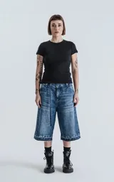 Bermuda larga de denim azul con lavado ácido y efecto desgastado. Presenta un calce oversize, talle alto con cinturón de tela a juego y ruedos deshilachados.