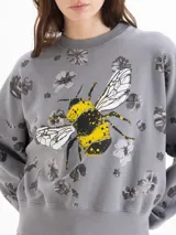 Buzo de algodón gris con estampa de abeja en el centro y diseño de flores oscuras dispersas por toda la prenda. Cuenta con cuello redondo, mangas largas y puños y cintura elastizados.