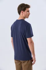 Remera azul marino de manga corta con cuello redondo y estampa frontal de un paisaje de playa con palmeras y el texto 'Legacy Beach Club'.
