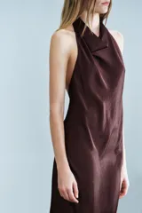 Vestido midi de tejido satinado en color marrón oscuro, con cuello halter de escote fluido, hombros descubiertos y cierre posterior con botones.