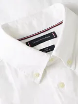 Camisa blanca de lino de manga corta con cuello abotonado y logo de Tommy Hilfiger bordado en el pecho.