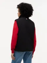 Chaleco negro con cuello chimenea, cierre de cremallera oculto con botones a presión y dos bolsillos laterales ribeteados. Presenta logos bordados en el pecho de Tommy Hilfiger y Cadillac Formula 1 Team.