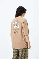Remera negra de corte holgado con mangas cortas amplias y cuello redondo. Estampado pequeño de flor en el pecho y estampado grande en la espalda con diseño floral y texto.