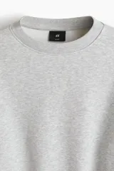 Buzo de cuello redondo color gris melange, de corte holgado, con hombros caídos y puños y dobladillo acanalados.