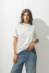 Camiseta de algodón orgánico de corte holgado, color blanco, con cuello redondo y logo pequeño bordado en el centro del pecho.
