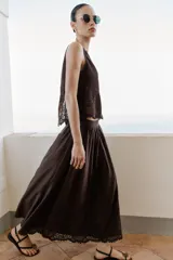 Falda midi marrón oscuro, con diseño fluido y voluminoso, tiro alto y detalles de bordados a tono en el ruedo.
