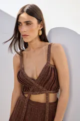 Top corto color marrón con hilos dorados, escote en V, tirantes finos y diseño cruzado en la parte delantera que se anuda en la espalda.