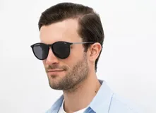 Lentes de sol INVU con montura redonda negra y lentes grises polarizadas.