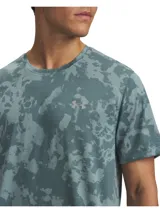 Remera deportiva Under Armour de manga corta, con estampado camuflado en tonos de verde, cuello redondo y el logo reflectante de la marca en el pecho.