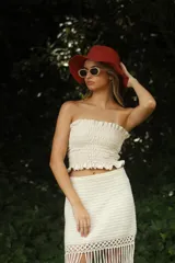 Top color crudo, sin mangas, con frunces en el busto y volados en el ruedo.