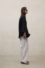 Blusa de lino blanca de corte amplio, con escote en V, mangas largas y puños con abertura y lazo.