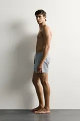 Short de baño confeccionado en tejido técnico con patrón de rayas verticales en tonos azul marino y blanco, con cintura elástica ajustable mediante cordón y bolsillos laterales.