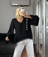 Blusa de tela cey color bordó, con escote en V y mangas largas abullonadas que terminan en puños con detalle de encaje y volados.